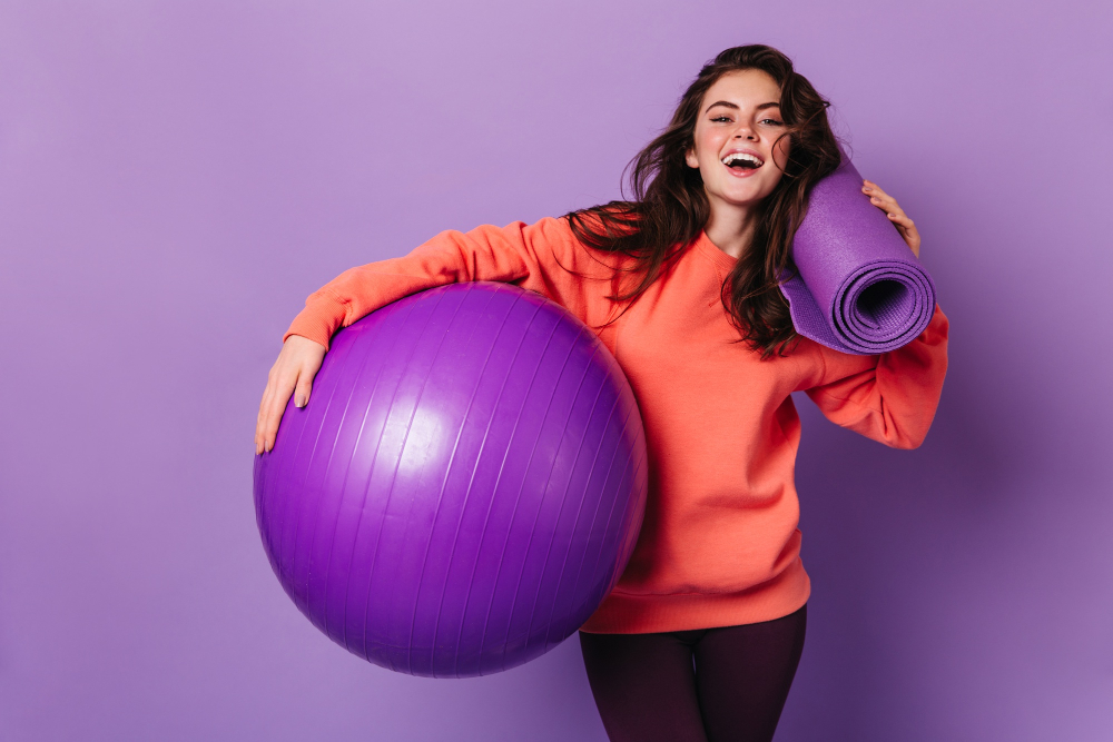 beautiful-woman-leggings-bright-sweatshirt-is-smiling-posing-with-purple-mat-fitball