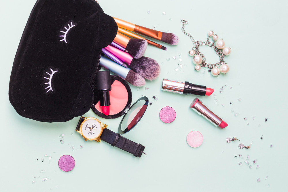 black-bag-with-makeup-brushes-bracelet-wristwatch-cosmetics-product-pastel-background