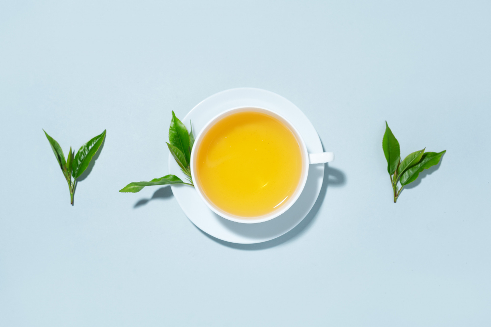 green-tea-brewed-cup-with-tea-leaves-blue-pastel-background-top-view